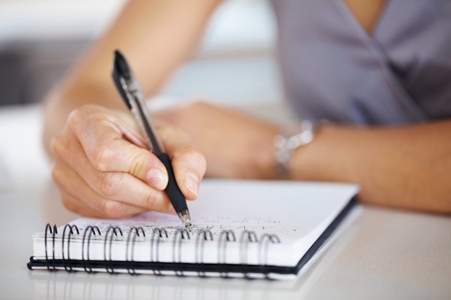Cropped image of hand of young woman taking notes